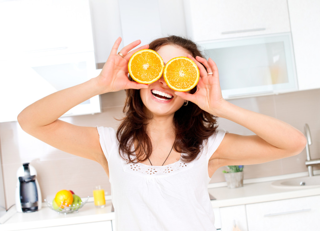 Portrait of Young and Healthy Funny Woman with Orange over Eyes