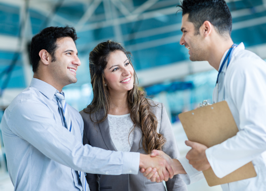 Family doctor handshaking a couple
